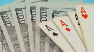 The hand drops a wad of hundred-dollar bills on the playing card table.