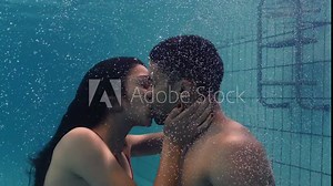 young couple kissing underwater in swimming pool enjoying intimate kiss romantic lovers submerged in water floating with bubbles in passionate intimacy