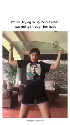 WatchThisOnce on Instagram: "Whyyyy A woman stands on an outdoor patio next to a glass-topped table, enthusiastically grooving to upbeat music while holding the tabletop in her hands. She energetically lifts it high above her head, twirling and dancing with surprising commitment and flair, as if performing an impromptu routine. Suddenly, she lowers the table in a dramatic motion, ducking underneath it—only for her head to become trapped between the glass surface and the frame. She freezes in stu