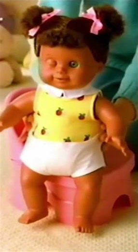 A baby doll sitting on top of pink chair