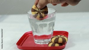 Bread and a glass of water. Biscuits are dipped in white water from transparent glass.Footage The snack dishes are conceptualized with studio quality