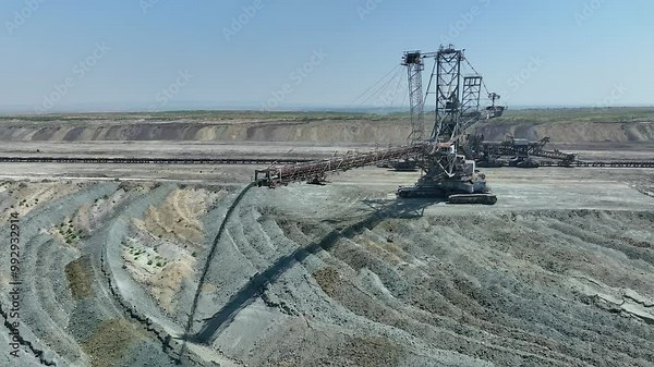 Top shot of a large bucket-wheel excavator in a lignite (brown-coal) mine. Аerial view. Coal transshipment. Flies over A heavy coal mining machine shovels coal with a bucket. Open pit. Green deal.