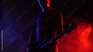 Hipster guy plays bass guitar on stage in smoke. Slow motion. Music, Sound, Band, Concept.