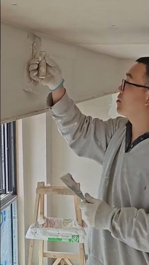 applying white putty to the interior wall and ceiling surfaces using a hand tool for smoothing