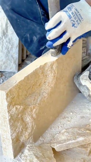 making a stone tile decorative pattern by using a handheld metal chisel and a small hammer on a wall