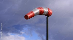 Wind sock blowing indicating wind direction against an cloudy sky