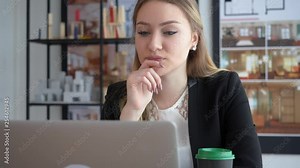 Satisfied young designer reading on her laptop. Beautiful businesswoman reading and smiling at her working table. Young designer architect closeup front view face