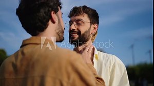 Silhouetted against fading light, two gay men share profound moment, one caressing other's face before tender kiss. Romantic, intimate gesture between LGBTQ couple, one partner hug and kiss another