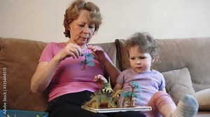 Grandmother and granddaughter play toys when left alone at home. Grandparent and grandchild activity concept.
