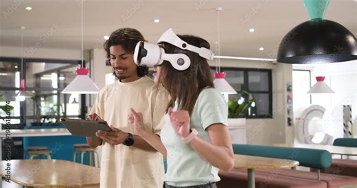 African American pair testing VR at lounge, man tapping tablet starting sim while woman gesturing