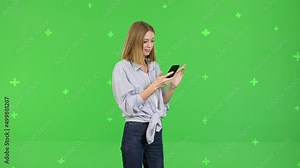 Girl reading text message on her mobile phone over green screen background, chroma Key 4k raw video footage slow motion 60 fps