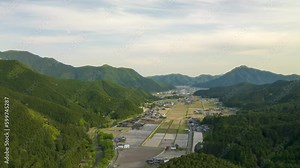 Aerial Time Lapse: Rice fields and village on plain in mountain landscape