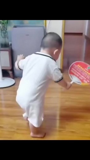 Toddler Explores Room with Handheld Fan in White Outfit