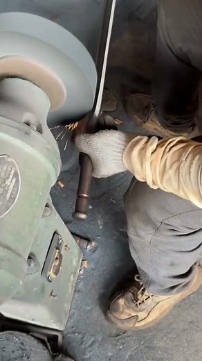 grinding a long knife blade with a special grinding machine in a blacksmith's workshop