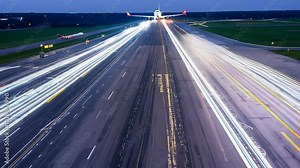 Airplane taking off from runway at night with lights.