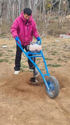 drilling a circular hole on a brown soil surface using a manual power earth auger machine for farm