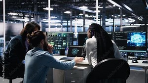 Teamworking data center technicians using machine learning algorithms to analyze large datasets. Server room colleagues gathered together at desk, collaborating, using AI neural networks, camera A