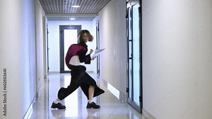 Successful job interview. Young girl walking out room and starting emotionally dancing in office lobby, crazy funny dance, celebration of success. Concept of business, emotions, joy, office, lifestyle
