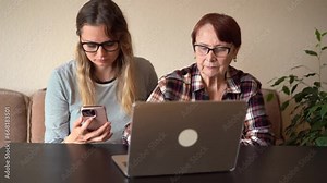 Granddaughter tells her old grandmother how to use a laptop.