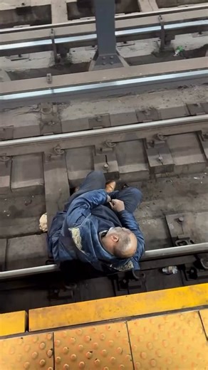 Cops in NYC dump water bottles on a homeless man who was sleeping on the subway tracks.Waiting passengers cheer when the man is finally dragged out of the way.