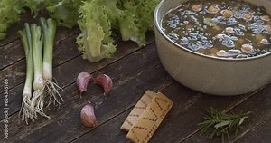 Curly endive and chickpea soup. Main ingredients shown: curly endive, garlic, Parmesan rind, scallions. Italian cuisine. Table spin.