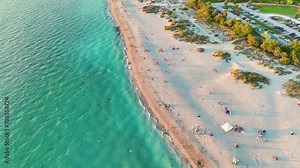 View from above of evening Blind Pass beach with white sands and relaxing tourists on Manasota Key, USA. People enjoying vacation time swimming in Mexica gulf water and resting on warm Florida sun