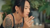 4K video footage of an Asian tattooed woman smoking a cigarette...