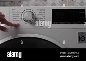 Close-up of a womans hand operating a modern washing machine, pressing buttons and selecting washing modes on the control panel