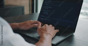 Close up male programmer whiting programmer code on his laptop computer. Digital Workspace, Man Software Engineer Programming on Laptop, Rear View in Office Setting. Coding, IT start up concept