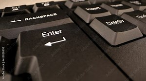 Finger presses and keeps large Enter button pressed on black keyboard under bright electric light extreme closeup. Concept ask question