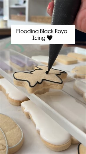 Flooding with black royal icing might look spooky 👻 but here’s the trick to getting dark colors without oversaturating: Mix to dark gray & let it rest overnight. The color deepens naturally so you use less gel (and avoid bleed). Stick with a medium-thick flood (10–15 sec) for stability. Dry with a fan to lock it in fast. Patience technique = bold colors that don’t bleed. 🖤 What’s your biggest struggle with dark icing? | The Cookie Curator, LLC