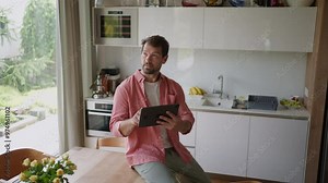 Handsome man adjusting smart home settings on touch screen device. Smart home technology for sustainable living.