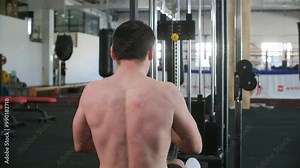 Rear view of shirtless athlete exercising with cablerow machine. Young sportsman is doing strength training in gym. He is working out in healthcare centre. Stock Video