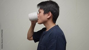 Chinese man drinking from a cup, it could be coffee, water, tea, or any other beverage