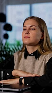 Tired long-haired young woman finished her work on computer. Lady put her head on the elbows and closes eyes to have some rest. Vertical video