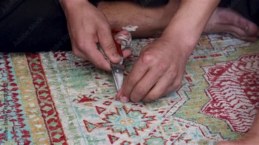 Artisan trims excess threads from a carpet using scissors with manual precision, Kabul, Afghanistan