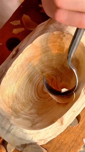 Hand carving the interior of a wooden bowl, smoothing the surface with a curved gouge