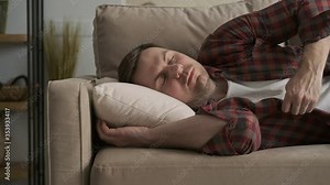 Portrait of handsome guy napping on sofa at home. Tired man in red shirt sleeping on couch. Guy relaxing in 4K, UHD Stock Video