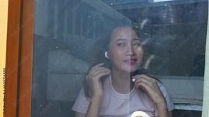 Young Asian woman listening to the music with earphones and mobile app in bedroom. Attractive girl using AI reading or searching data on mobile phone application at home.