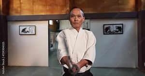 Aikido, katana and master fight with a sword in traditional Japanese class, gym or competition. Martial arts, sensei and mature fighter training with weapon for sport or practice of defence technique