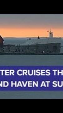 Freighter cruises through Grand Haven at sunset