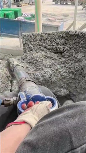 Using a breaker tool, he breaks hardened cement stuck inside an iron container for cleaning easily