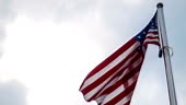 United States American flag flying from a flagpole in a wind showing...
