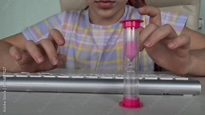 Girl child teenager typing text on computer keyboard with hourglass. Controlling children's time on the Internet and online games