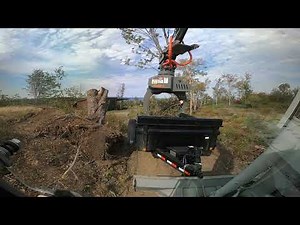 Excavator with fixed rotating grapple saw pulling and loading dump trailer