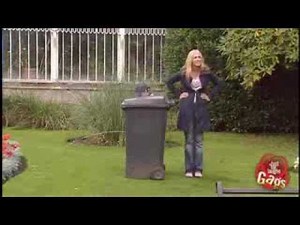 Boy peeing behind trash can outside.