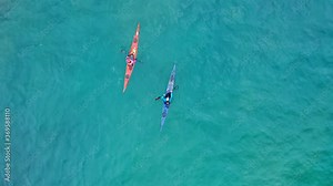 4K overhead aerial view of two men kayaking in the teal clear waters. Vibrant colorful kayak boats are in the open ocean. Extreme sport, outdoor travel, active people. Perfect still sport background