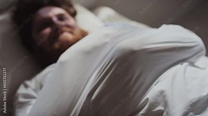 Selective focus shot of young male patient wearing straitjacket lying on hospital bed trying to free his handsSelective focus shot of young male patient wearing straitjacket lying on hospital bed tryi