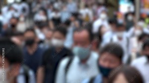 TOKYO, JAPAN - JUL 2020 : Crowd of people at the street near Shinjuku station in rush hour. Commuters wearing surgical mask to protect from Coronavirus (COVID-19) in hot summer. Blurred slow motion.