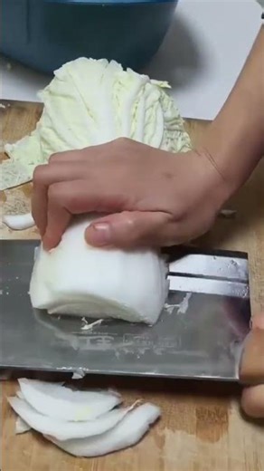 Hand slicing napa cabbage into clean uniform pieces on board